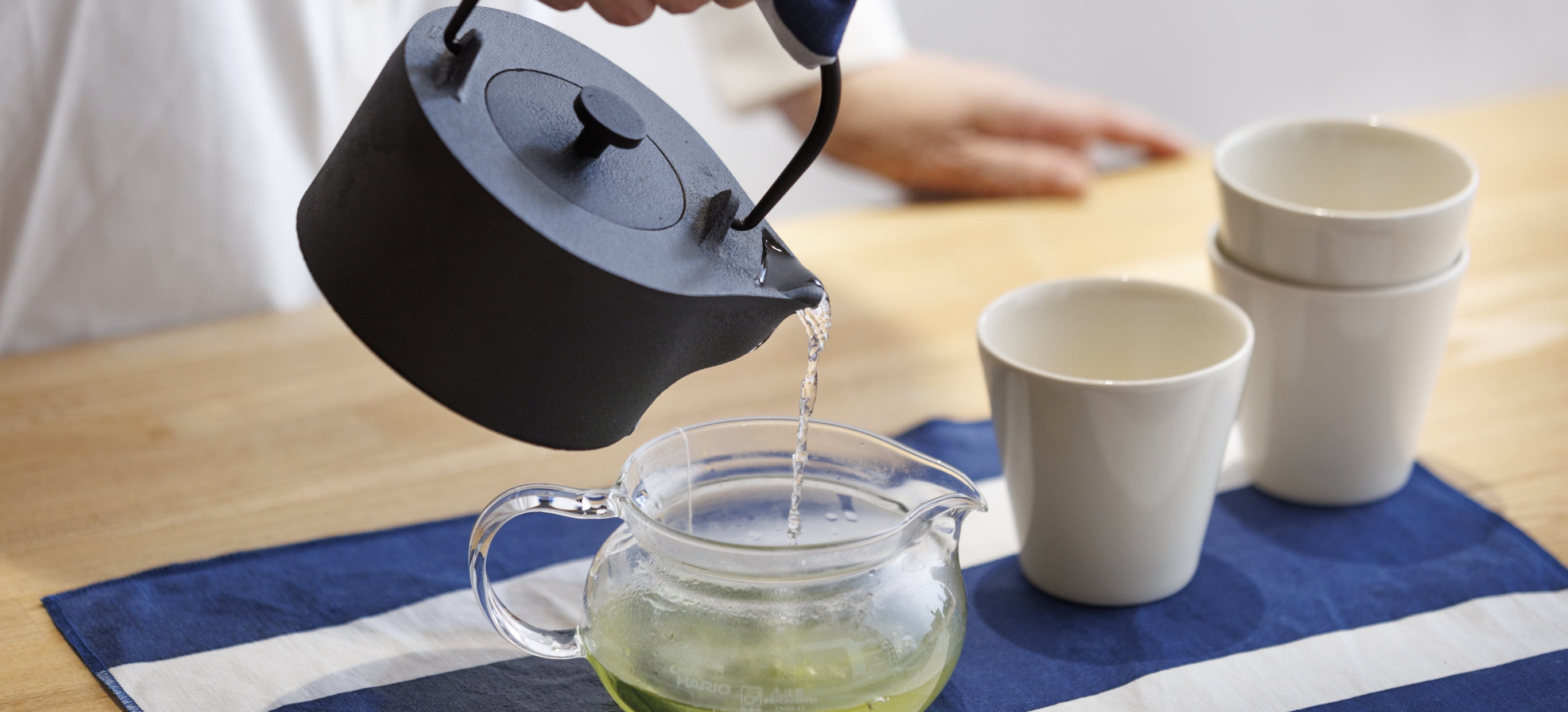 キッチンクロスの上にポットを置き、お茶を注いでいる様子